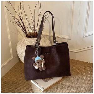 Detail of coffee brown quilted tote bag with suede texture and cute bear charm