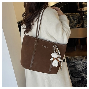 Detail of dark brown suede tote bag featuring a teddy bear charm and silk scarf