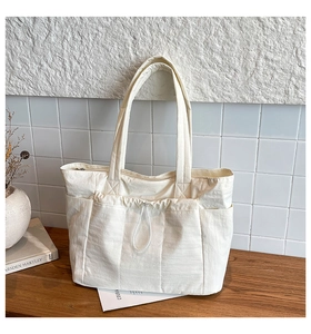 Détail du grand sac cabas blanc cassé avec poches à cordon et texture en nylon souple