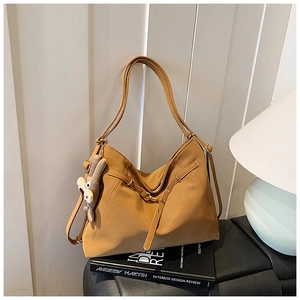 Detailed view of a caramel leather tote with a gray bunny charm on a minimalist desk