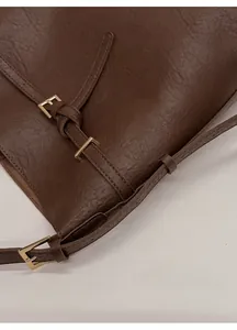 Detail of retro dark brown bucket bag showing fine stitching and gold metal buckle