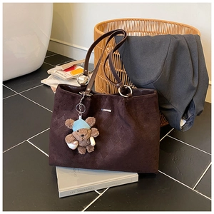 Detailed macro view of coffee brown tote bag with quilted pattern and plush bear charm