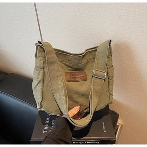 Detailed shot of an army green canvas tote with a brown leather tag and side pocket