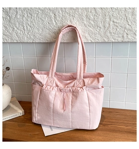 Vue détaillée du sac cabas matelassé rose avec poches latérales et cordon