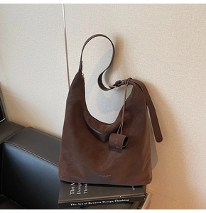 Detail of dark brown suede hobo bag with text accent placed on black books