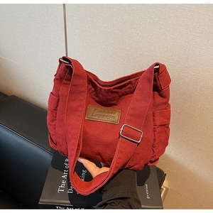 Close-up of deep red canvas tote bag with adjustable shoulder strap and leather patch