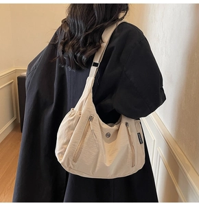 Détail du sac hobo en nylon crème avec fermetures éclair et bandoulière réglable