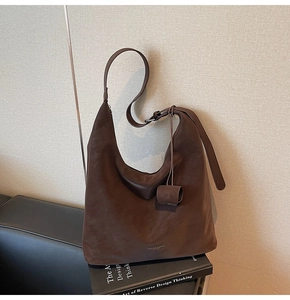 Detail of coffee brown leather hobo bag with wide strap on black book display