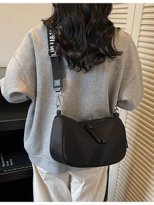 Fashionable black nylon crescent crossbody bag with woven tassel details and wide strap
