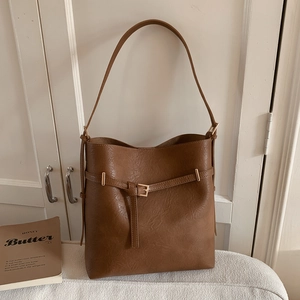 Detailed close-up of brown bucket bag with lychee texture and golden buckle hardware