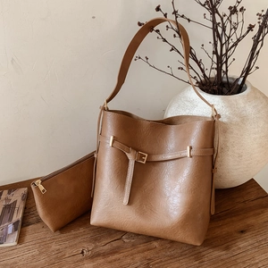 Brown faux leather bucket bag set with textured finish and inner pouch on wooden surface