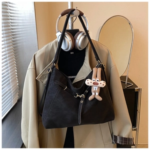 Detailed view of a black faux leather tote bag with metal buckle and plush rabbit charm