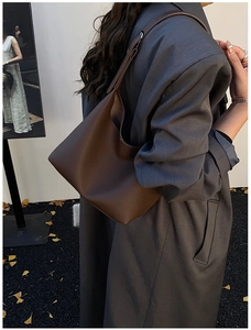 Detail of dark brown pebble leather tote bag worn with a gray wool blazer for autumn