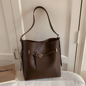 Detail of dark brown bucket bag featuring gold buckle and textured vegan leather