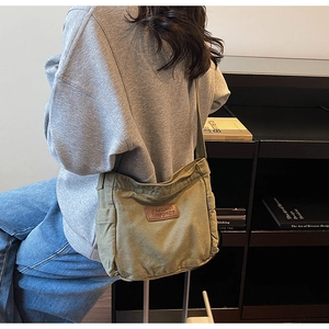 Olive green canvas crossbody tote bag with adjustable strap shown in a lifestyle setting