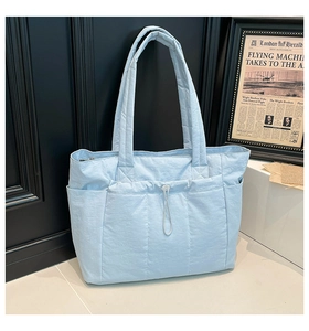 Détail du sac cabas en nylon matelassé bleu clair avec poches extérieures et cordon de serrage