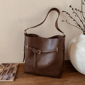 Detail view of dark brown bucket bag featuring buckle decoration and retro style design