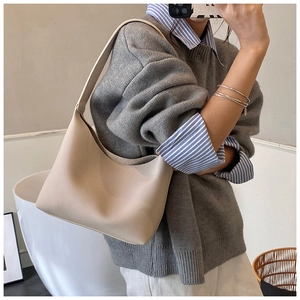 Detail of beige lychee textured leather hobo bag with wide shoulder strap on a model
