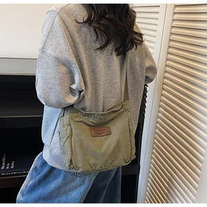 Detail of vintage green canvas tote with brown leather label and side pocket design