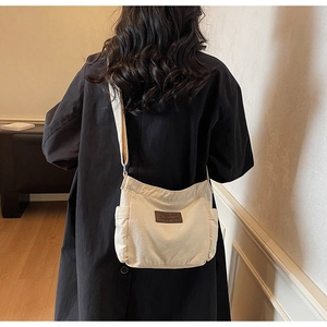 Detail of off-white canvas crossbody bag featuring leather patch and side pocket detail