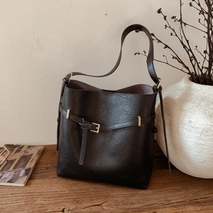 Detailed macro shot of black textured bucket bag with gold square buckle and leather strap