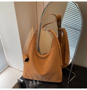 Detail of a brown orange leather hobo bag with wide strap reflecting in an oval mirror