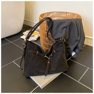 Detail shot of black tote bag with gold hardware and curved stitching on its leather surface