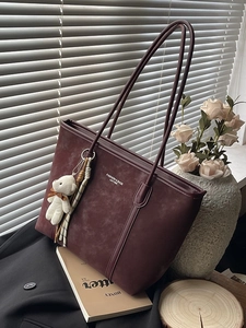Burgundy suede tote bag with fashion lettering and cute white bear charm on office desk
