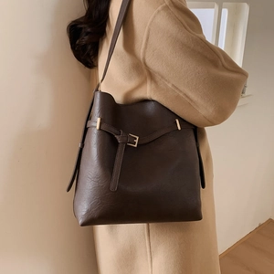 Dark brown bucket bag with gold buckle detail worn with a camel coat for daily commute