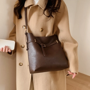 Detail of dark brown vintage bucket bag with litchi grain texture and buckle strap