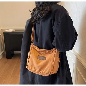 Close-up of caramel canvas tote bag with leather logo detail and wide shoulder strap