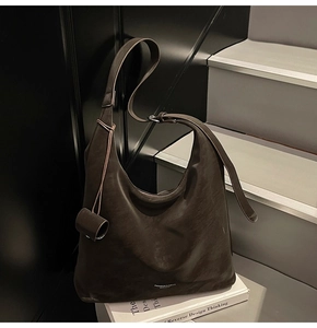 Detail of dark brown leather hobo bag with embossed fashion text and soft matte texture