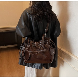 Detail van de donkerbruine leren shopper met trekkoordsluiting en zilverkleurige accenten