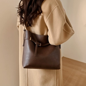 Detail of vintage dark brown bucket bag with lychee texture and buckle on a model