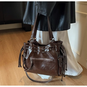 Détail du cabas marron foncé avec anneaux métalliques, cordon et poches zippées multiples