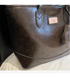 Detail of dark brown leather tote bag with bear embossed pattern and Sunny Day patch