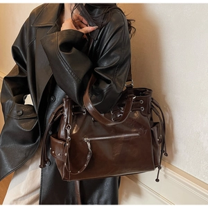 Détail d'un cabas en cuir marron brillant avec poche zippée et rivets décoratifs
