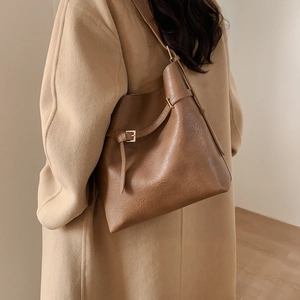 Detail of a large brown hobo bag with adjustable strap and textured leather finish