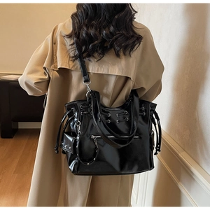 Détail d'un grand sac cabas noir brillant avec clous argentés et poche zippée