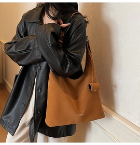 Close-up of brown leather tote bag with Fashion & Bags text on a model in black jacket