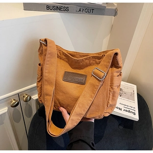 Detail of caramel canvas tote bag with leather logo tag and silver metal buckle