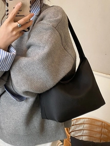 Minimalist black pebbled leather hobo tote bag for women shown in a casual lifestyle setting