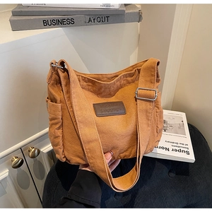 Detail of adjustable silver buckle and side pocket on brown canvas tote shoulder bag