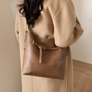 Brown leather bucket bag styled on a camel coat, showing professional commuting look