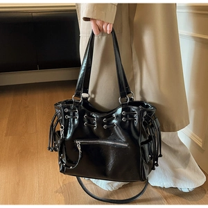 Détail du sac cabas noir brillant avec œillets argentés et cordon de serrage décoratif