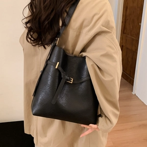 Close-up of black retro bucket bag with gold buckle detail and textured vegan leather