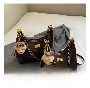 Detail of dark brown faux leather hobo bags with gold chain straps and teddy bear charms