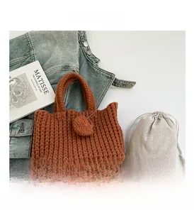 Detail of reddish-brown crochet tote bag with thick knit texture and cotton dust bag