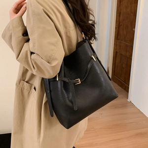 Detail of minimalist black PU leather tote with elegant gold metal buckle on shoulder strap