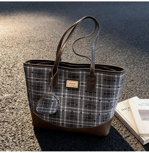 Detail of plaid tote bag with Sunny Day logo and leather trim on an urban asphalt surface